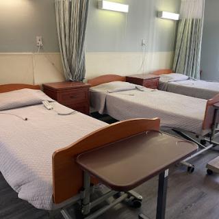 A view of a hospital patient room with multiple beds and medical equipment.