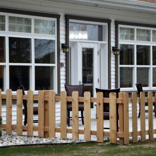 A cozy patio area of a house with large windows and a wooden fence.