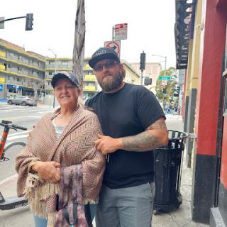 Two people posing together in an urban setting.