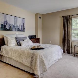 A cozy bedroom featuring a neatly made bed, elegant curtains, and wall artwork.