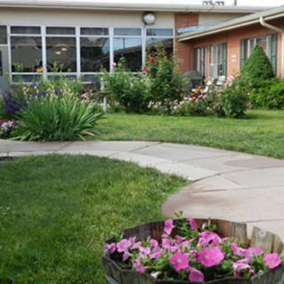 A garden with a stone pathway and blooming flowers leading to a building.
