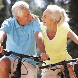 An elderly couple enjoying a bike ride together outdoors.
