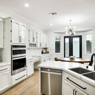 A modern kitchen featuring white cabinets, an island, and stainless steel appliances.
