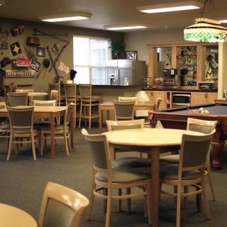 A recreational lounge with tables, chairs, and a pool table.