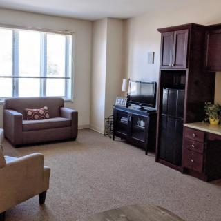 A cozy living room with armchairs, a television, and large windows.