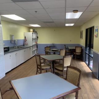 A well-lit break room with tables, chairs, and a kitchenette.