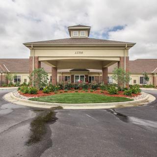 A well-maintained building entrance with landscaped surroundings and a driveway.