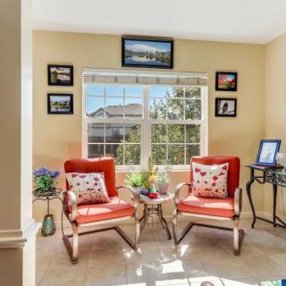 A well-lit living room with two red chairs and decorative elements by a large window.