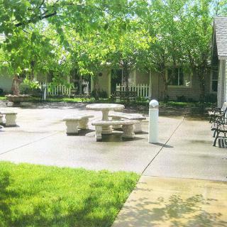 A peaceful courtyard featuring stone tables and benches surrounded by lush green trees.