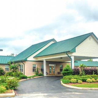 A modern building with a green metal roof and landscaped entrance.