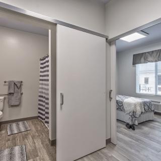 A modern interior featuring a bedroom and adjacent bathroom separated by a sliding door.