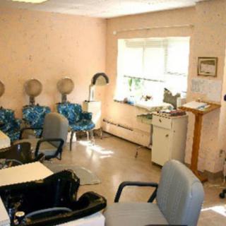 A cozy hair salon with chairs and hair dryers lined up against the wall.