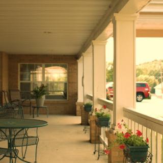 A cozy porch with plants and outdoor seating, perfect for enjoying the sunny weather.