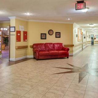 A brightly lit hallway with a red sofa against the wall, featuring tiled flooring and decorative elements.