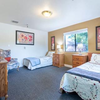 A cozy bedroom with two twin beds, featuring wooden furniture and a large window providing natural light.