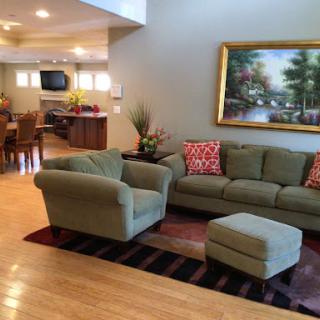 A spacious and inviting living room featuring a comfortable sofa, ottoman, and decorative artwork.