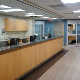A modern office reception area featuring a wooden counter and glass partition.