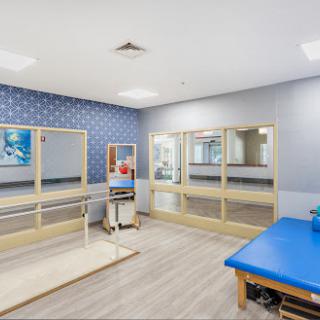 A well-equipped physical therapy room featuring mirrors, a treatment table, and various exercise tools.