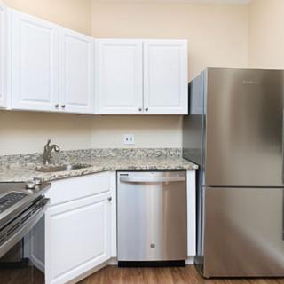 A modern kitchen featuring white cabinets, stainless steel appliances, and a granite countertop.