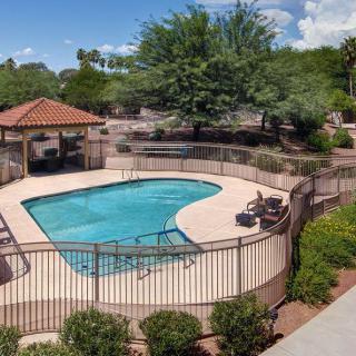 A fenced outdoor swimming pool area with seating and surrounding greenery.