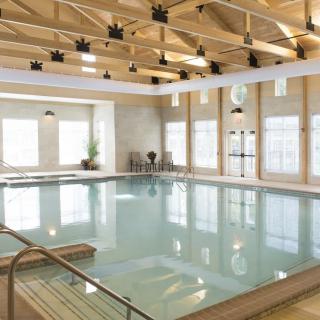 A spacious indoor swimming pool with a modern design and abundant natural light streaming through large windows.