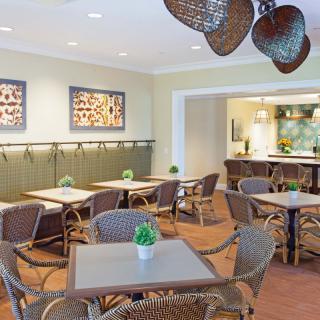 A cozy dining area with wicker furniture and decorative artwork on the walls.