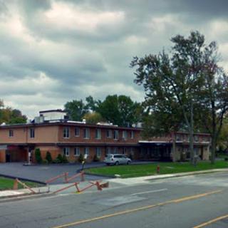 A motel stands along a quiet street under overcast skies.