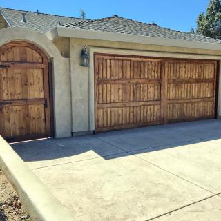 A residential garage with wooden doors and a paved driveway.