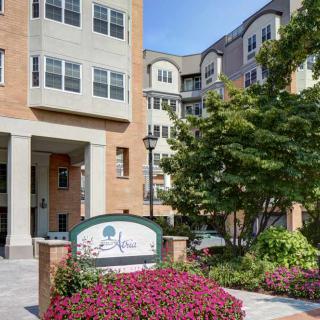 Entrance of a modern apartment building surrounded by landscaped gardens and vibrant flowers.