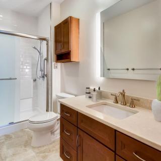 A modern bathroom with a walk-in shower, vanity sink, and wooden cabinets.