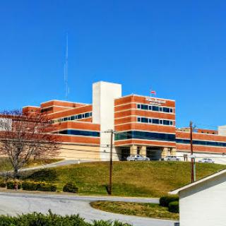 A brick hospital building stands under a clear blue sky.