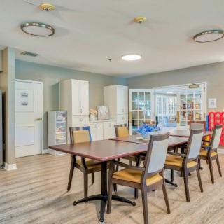 A modern dining room with a large table and chairs, featuring ample lighting and contemporary furnishings.