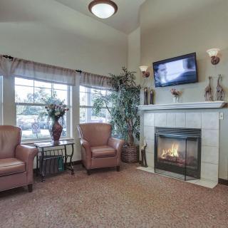 A cozy living room with a fireplace, armchairs, and a TV.