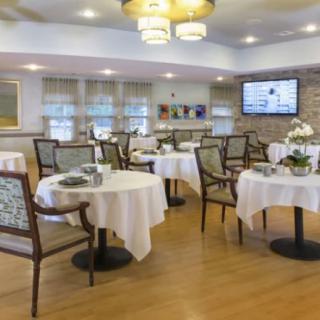 A well-lit dining area with neatly arranged tables and chairs, featuring elegant decor and a warm atmosphere.