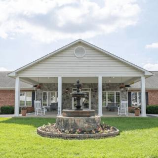 A suburban house with a front porch and a fountain on the lawn.