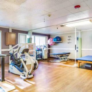 A well-equipped rehabilitation room with exercise machines and therapy tables.