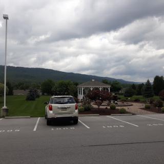 A parked car in a lot with a scenic view of mountains under a cloudy sky.