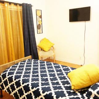 A cozy bedroom with a patterned bedspread, wall-mounted TV, and accent cushions.