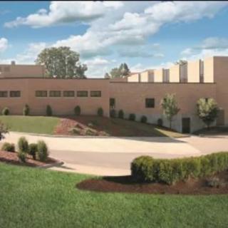 A modern building surrounded by well-maintained landscaping under a partly cloudy sky.