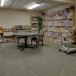 A quiet library room with shelves full of books, a round table, and chairs.