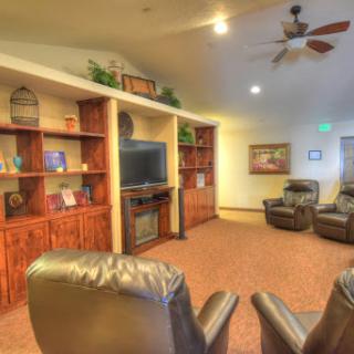 A cozy living room area featuring comfortable recliners and wooden shelves with a television, creating an inviting atmosphere.