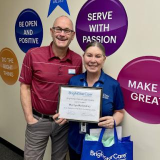 A moment of celebration as two colleagues proudly display an award in their workplace.