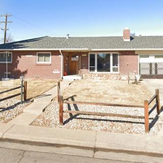 A suburban brick house with a front yard and fence.