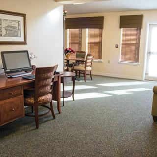 A sunlit office space with desks, chairs, and a computer.