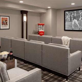 A cozy home theater setup with gray seating, a classic popcorn machine, and a movie playing on the screen.