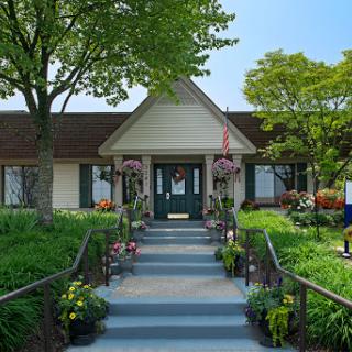 A welcoming entrance to a beautifully landscaped building, featuring vibrant flowers and lush greenery.