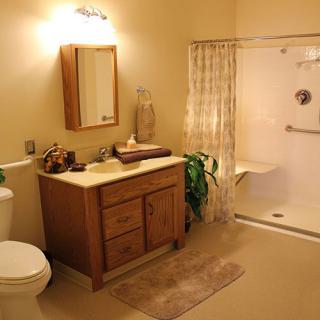 A clean and cozy bathroom featuring a wooden vanity, mirror, toilet, and walk-in shower.