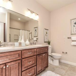 A modern bathroom interior with wooden cabinetry, a wide mirror, and stylish decor.