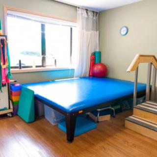 A physical therapy room equipped with a therapy bed, mats, and exercise equipment.