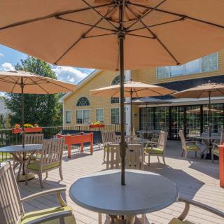 A sunny outdoor patio with tables, chairs, and umbrellas.